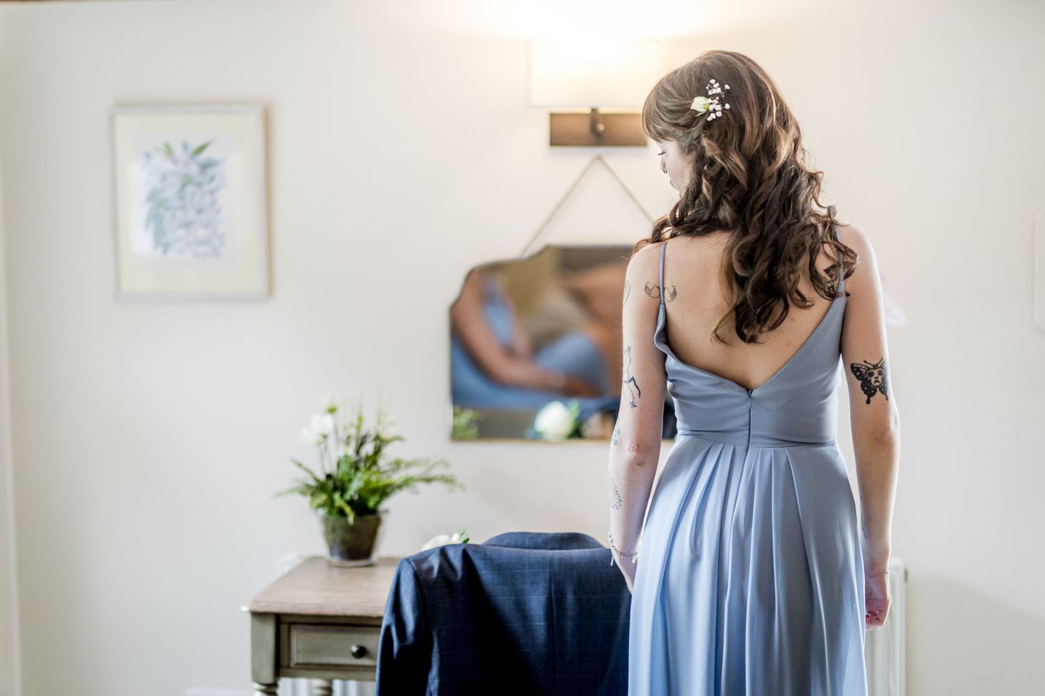 Bridesmaids in light blue dresses prepare for a wedding in a sunlit room.