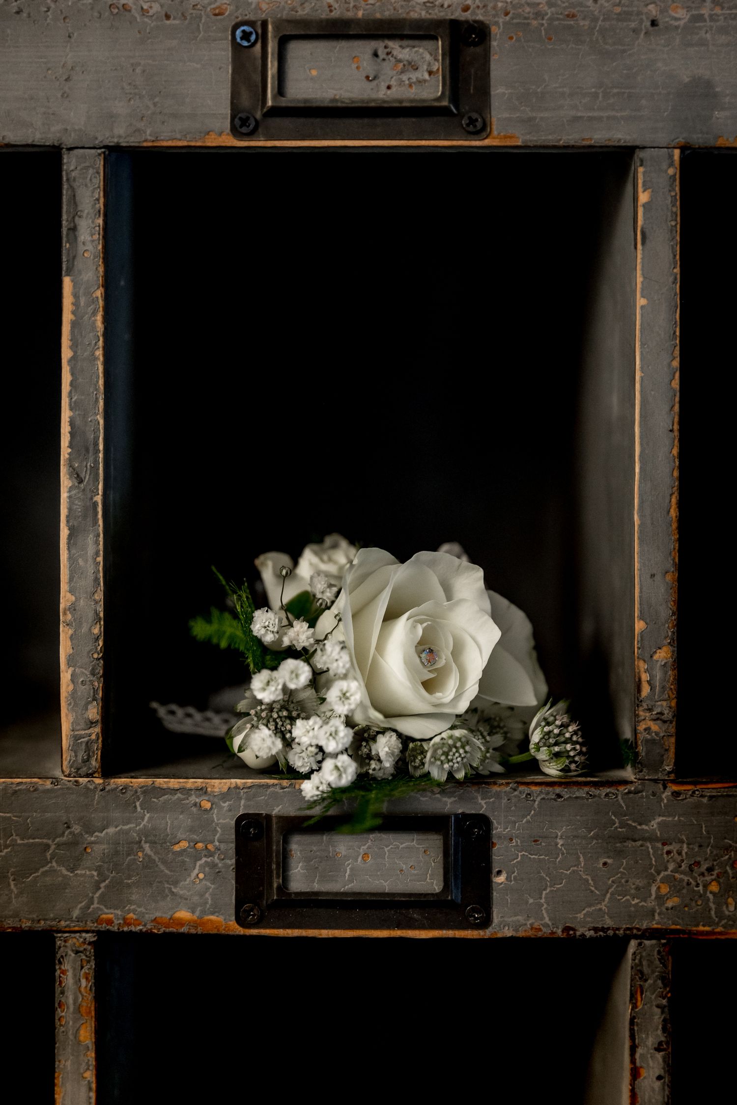 White roses and baby's breath flowers arranged in vintage window frame display.