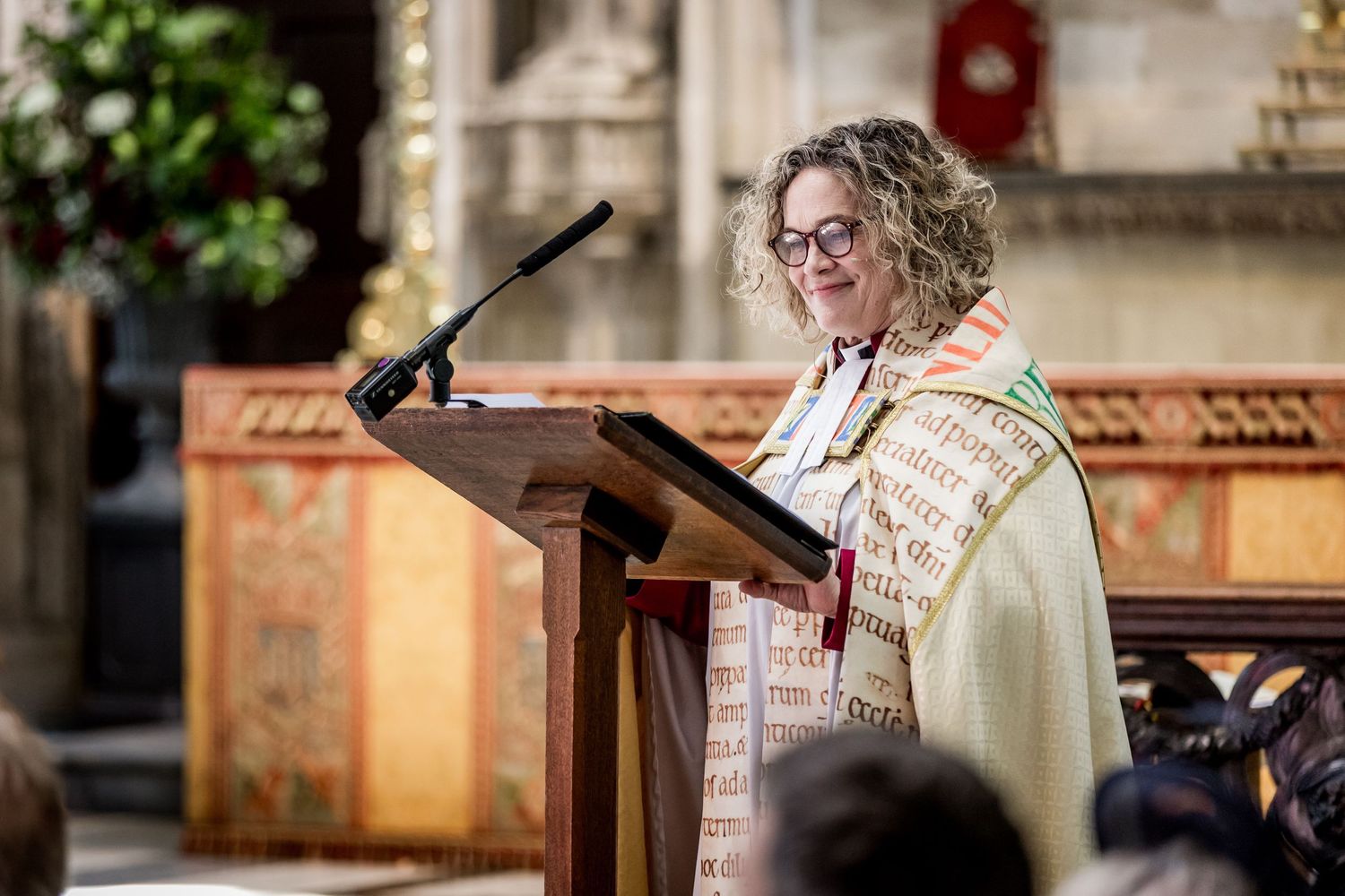 Wedding ceremony readings being delivered at ornate church podium.
