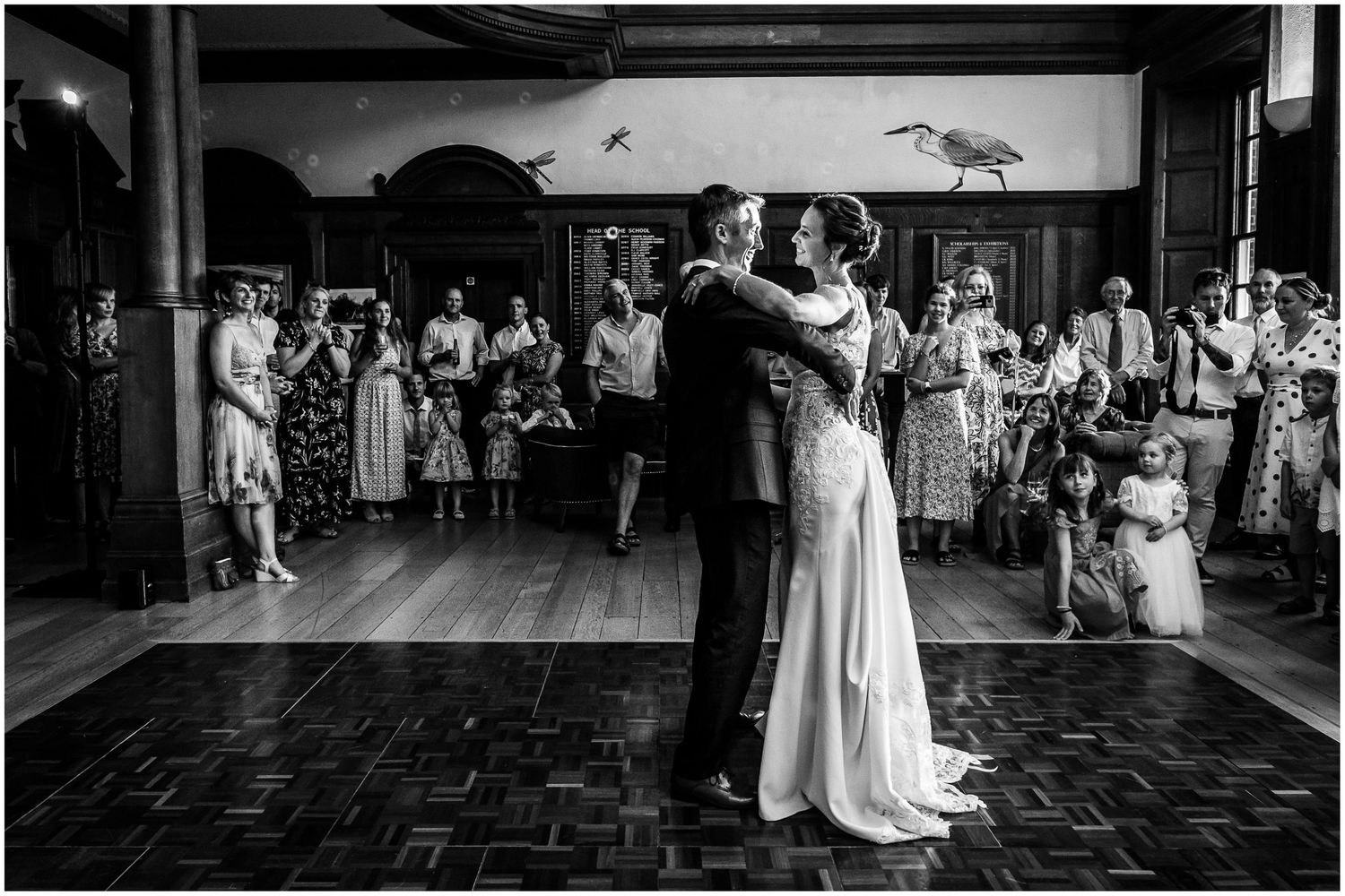 Black and white photo of a bride and groom sharing their first dance surrounded by wedding guests in the hall at Walhampton in Hampshire