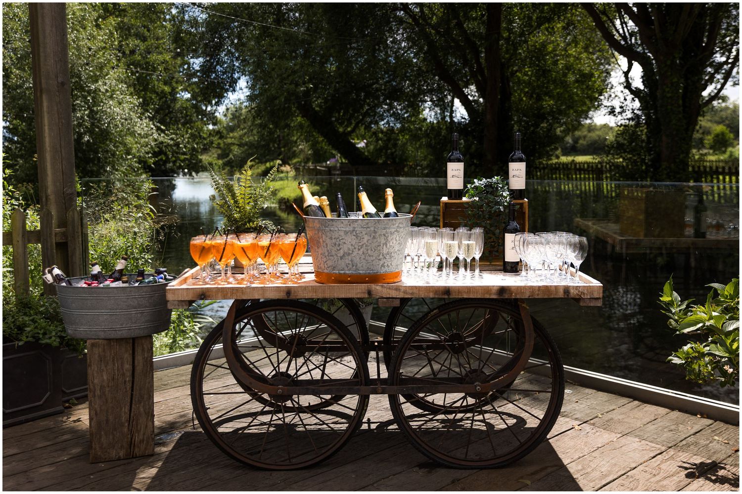 Outdoor drinks cart with champagne flutes, wine bottles, and ice buckets on the terrace at Sopley Mill, New Forest wedding venue