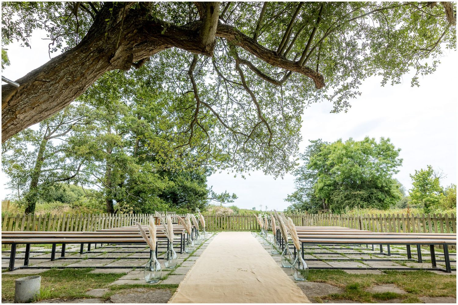 Tree-lined pathway with wooden fencing creating a natural outdoor corridor.