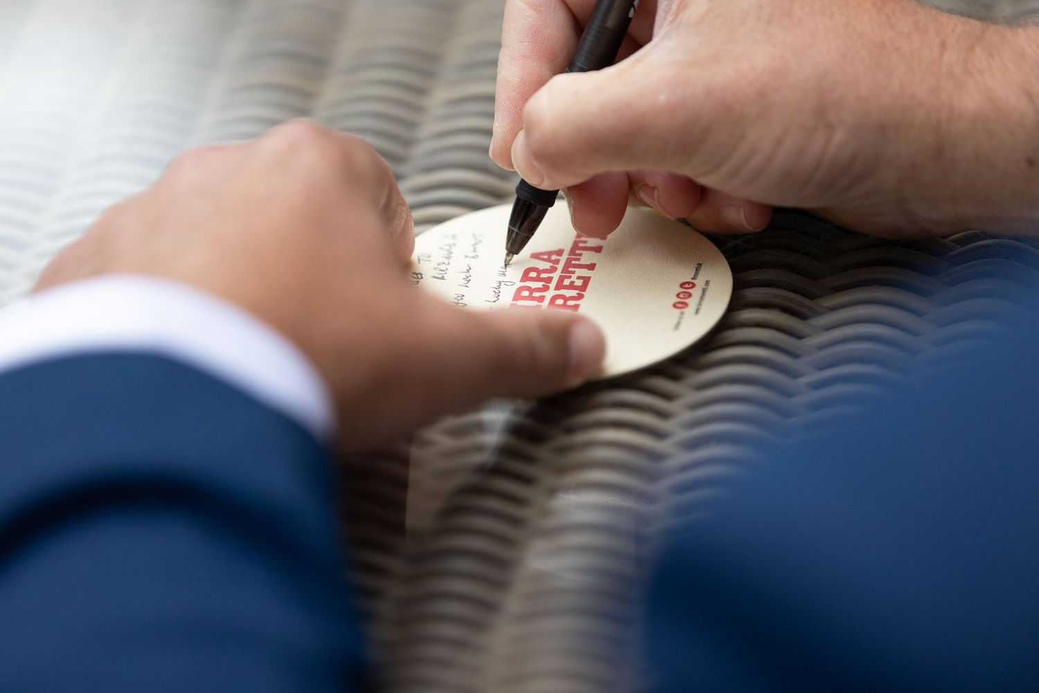 Close-up shot of hands signing or writing on paper during a formal occasion.