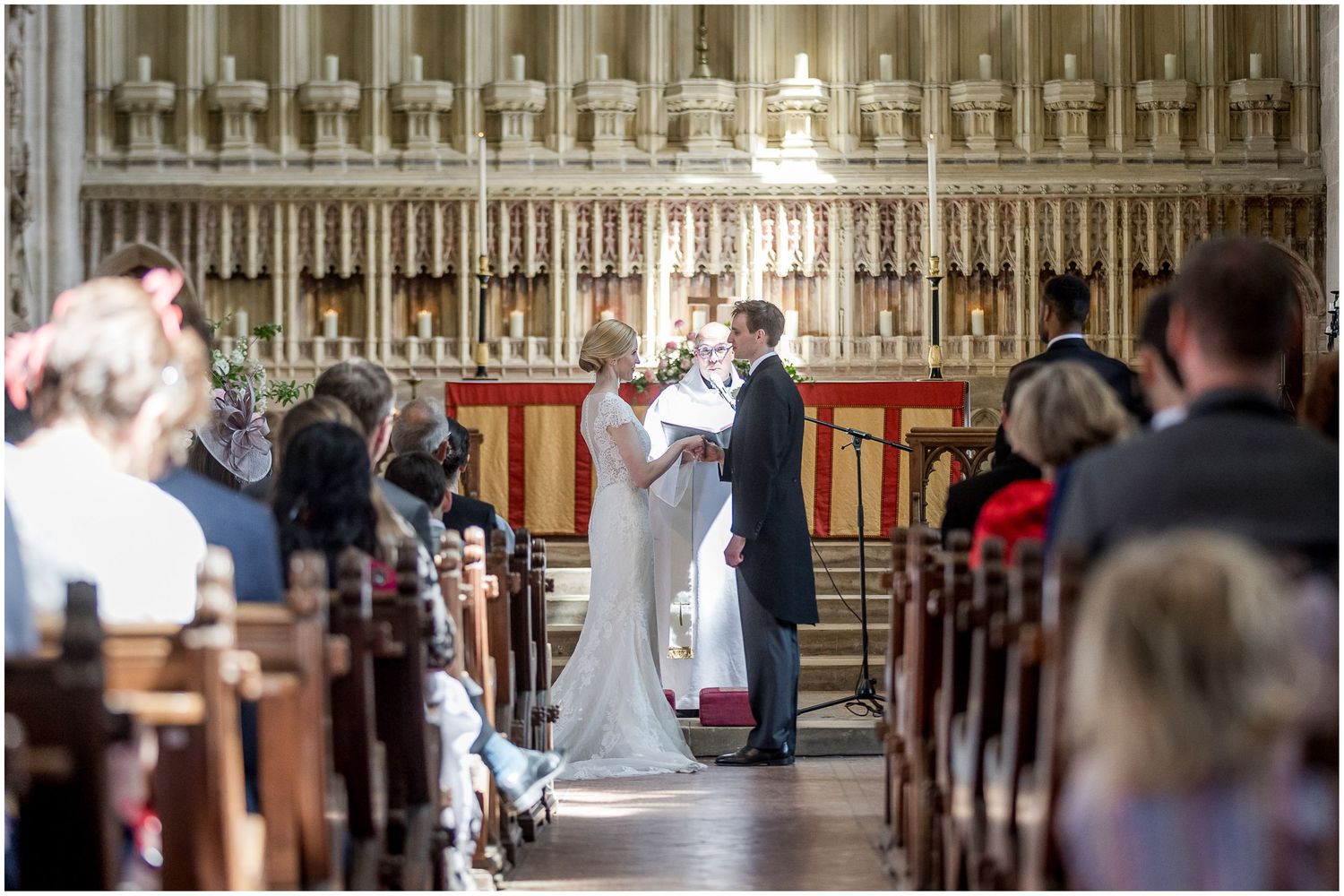 Wedding ceremony taking place in a grand cathedral with ornate architecture and wooden pews.