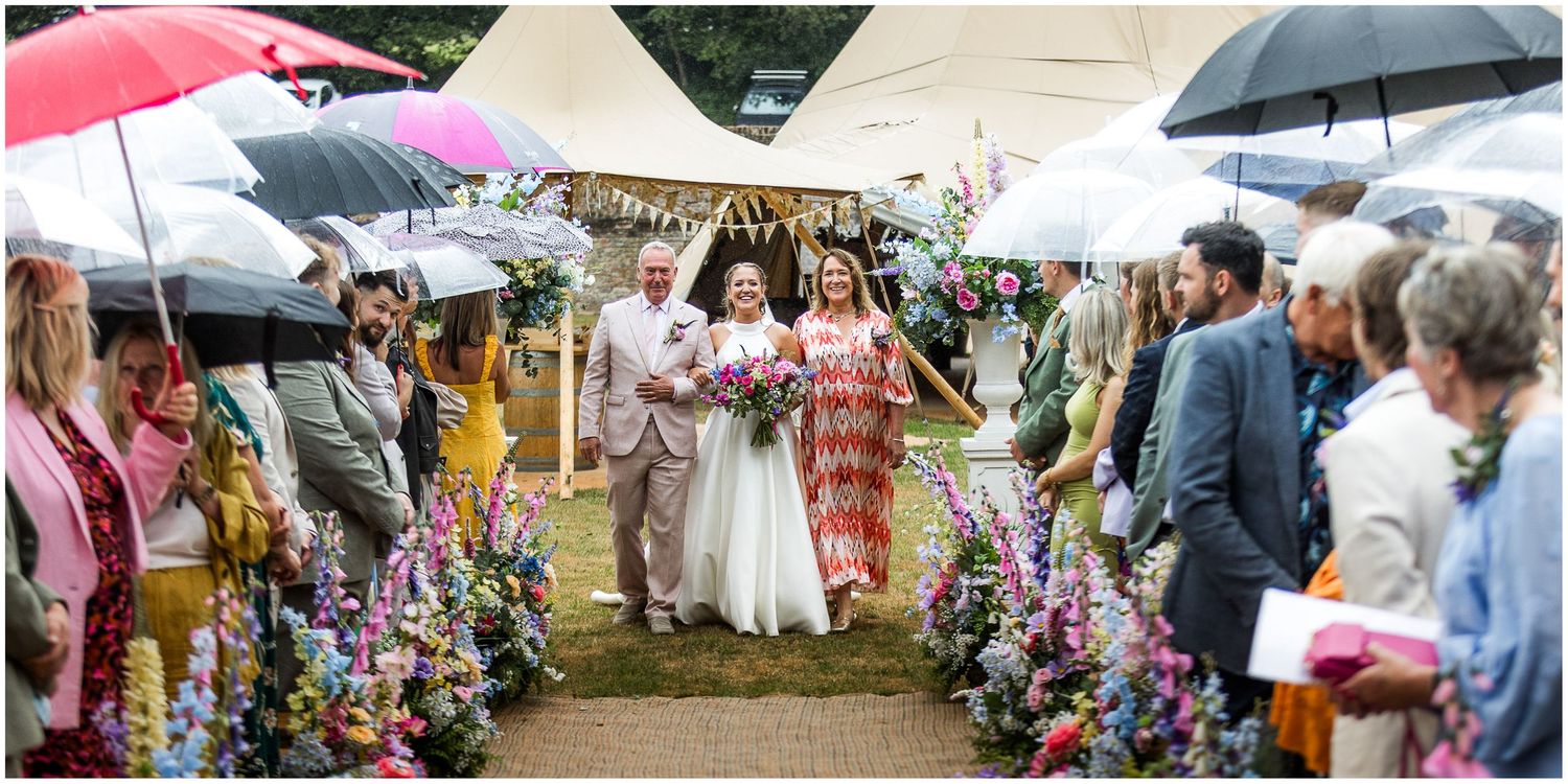 Documentary wedding photography of the bride walking down the aisle with her parents at the Holywell Estate near Hampshire