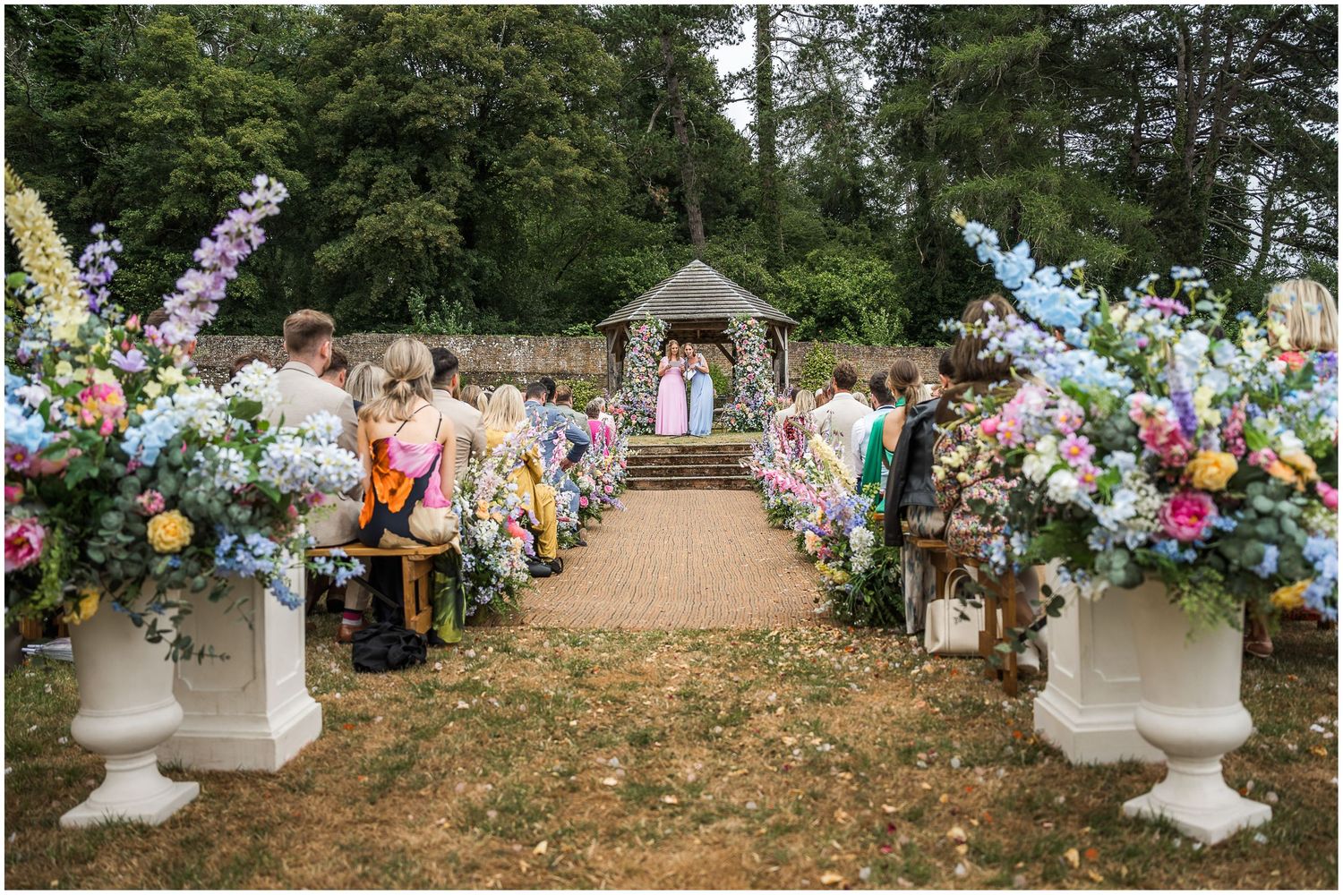 Wedding guests sit outdoors for the speeches as part of the wedding reception.