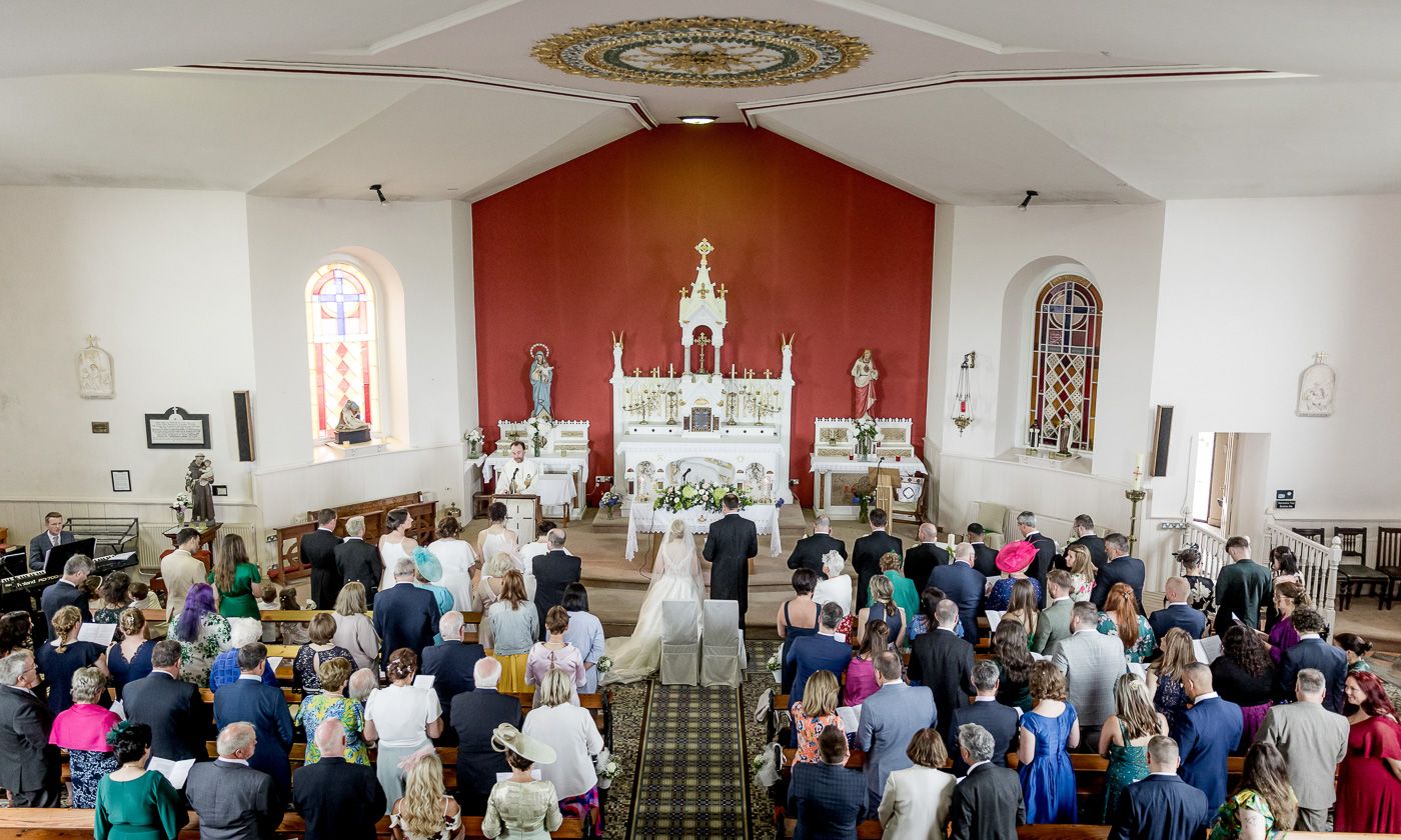 Panoramic view of church wedding ceremony with congregation in attendance.