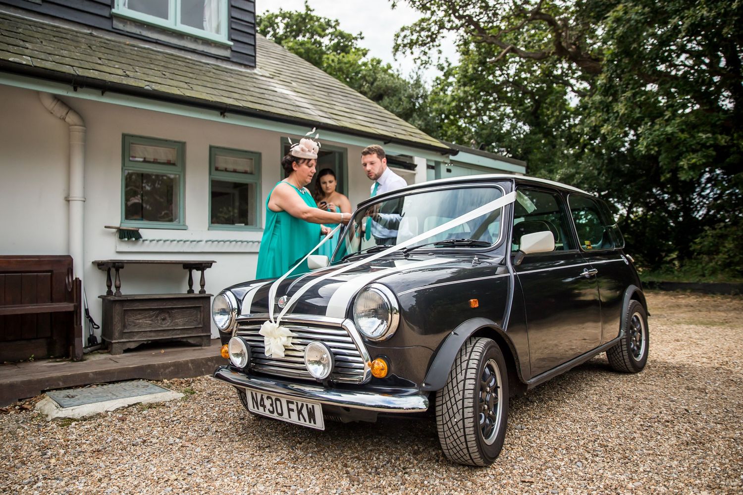 Classic vintage cars lined up on gravel driveway at wedding venue.