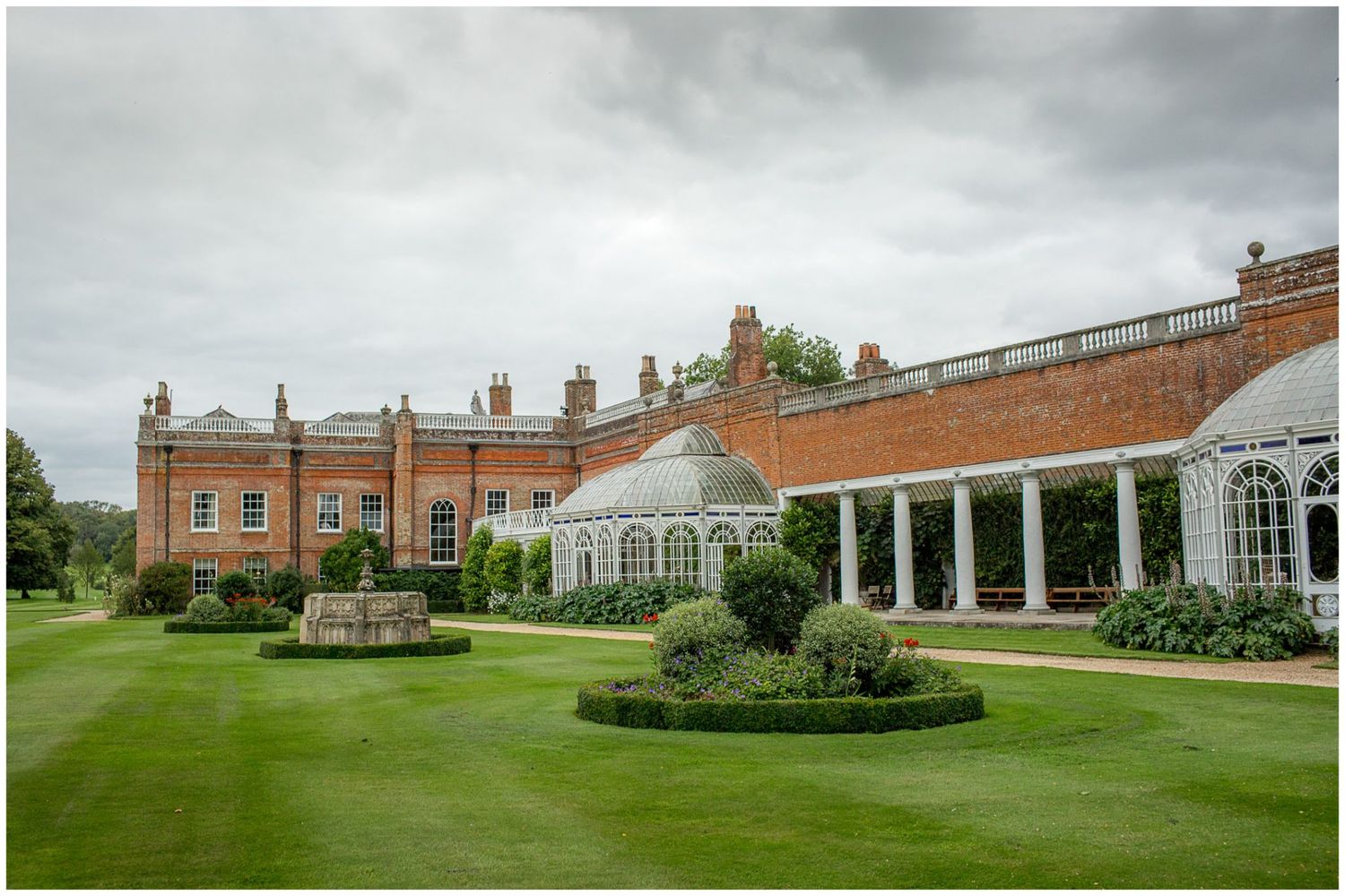 Panoramic view of a historic mansion and gardens with columned architecture.