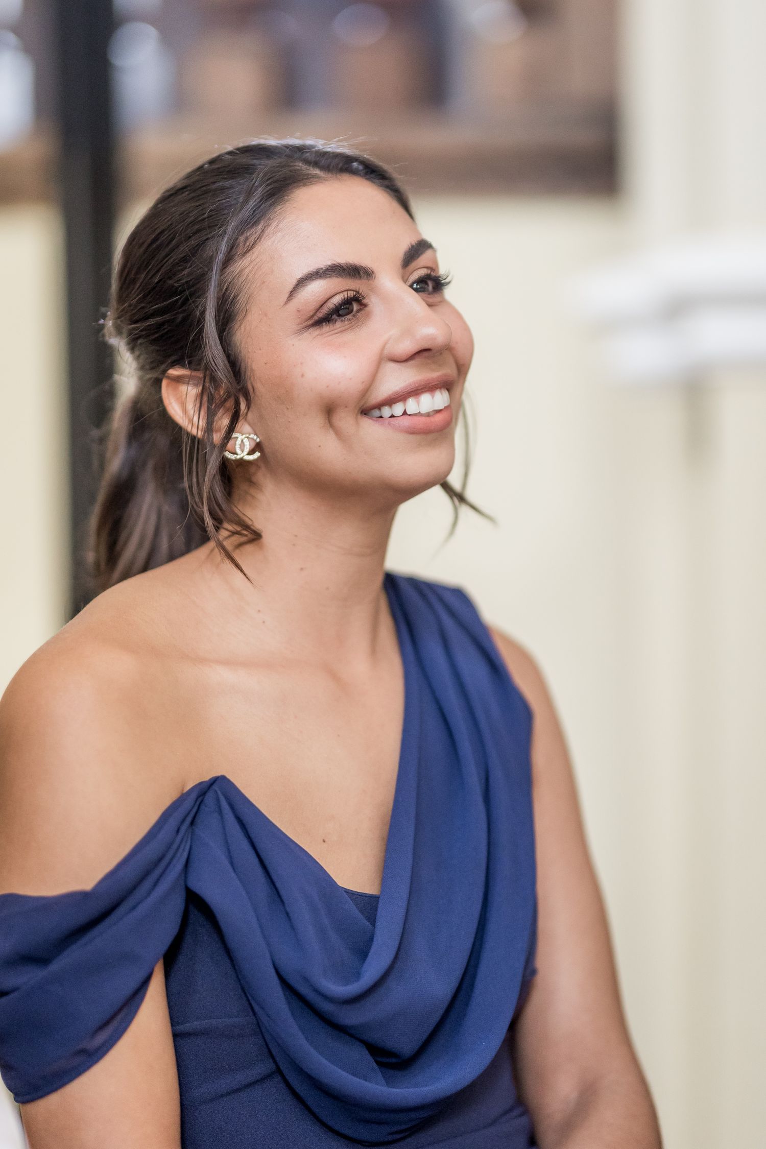 Guest in navy blue formal dress smiling during wedding reception celebration.