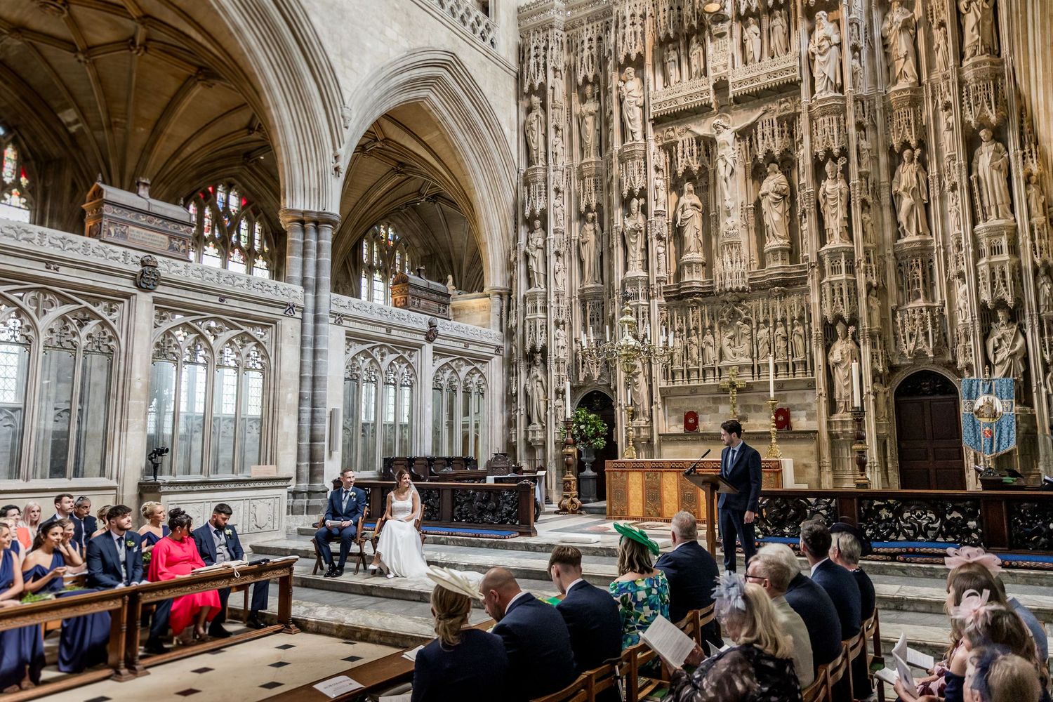 Wide view of Gothic cathedral interior during wedding ceremony with vaulted ceilings and stone columns.