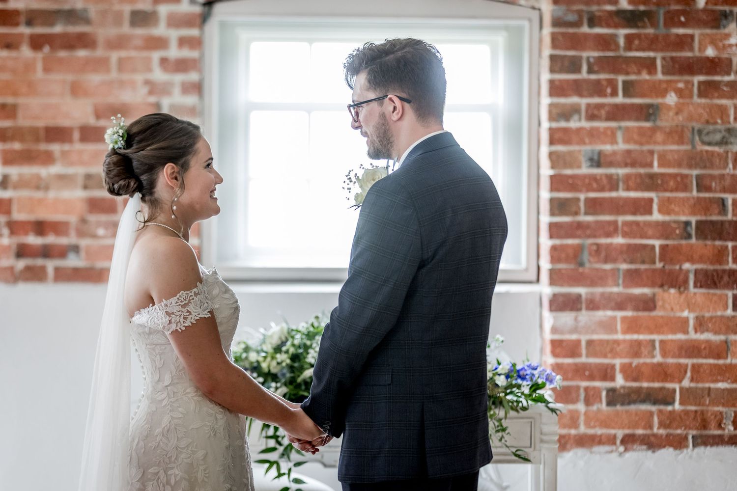 Intimate wedding ceremony moment in front of exposed brick walls and bright windows.