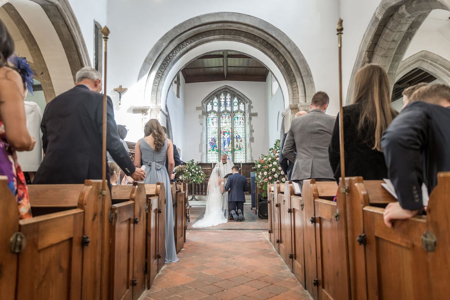 Interior view of church aisle with wooden pews and vaulted ceiling.