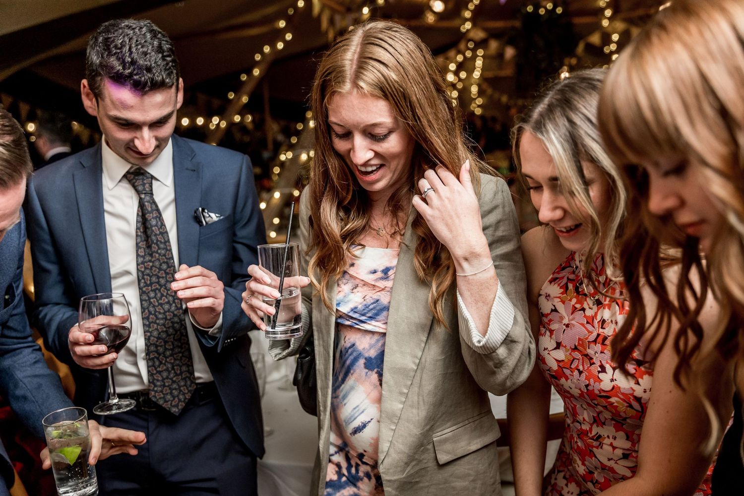 Wedding reception guests enjoying drinks and conversation in warm ambient lighting.