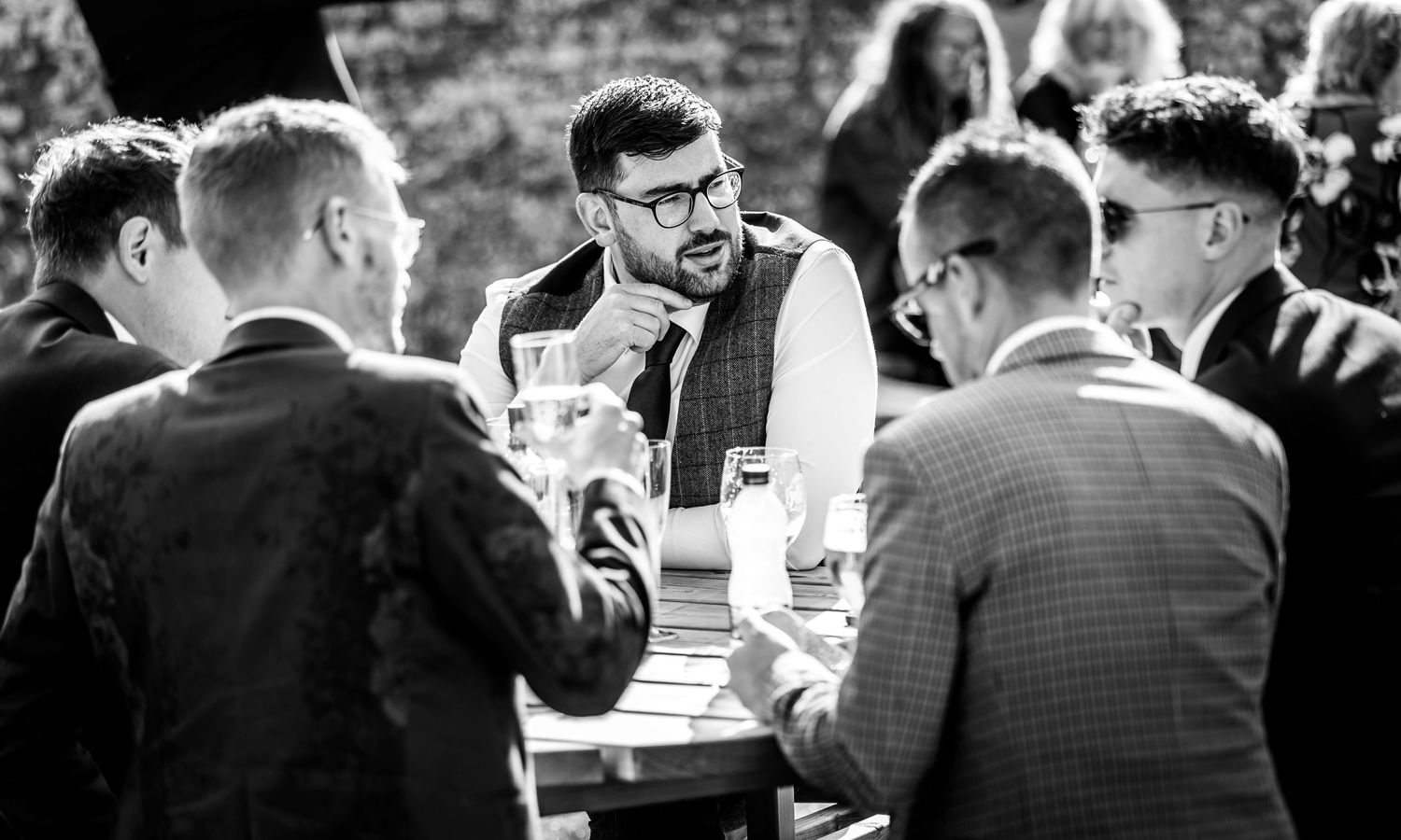 Black and white photo of guests socializing at an outdoor reception.