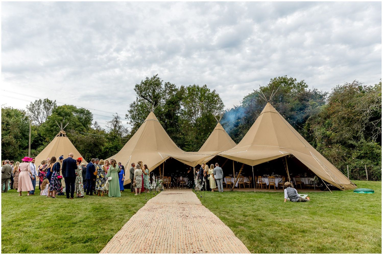Large tipi-style tents set up in a green field for an outdoor event.
