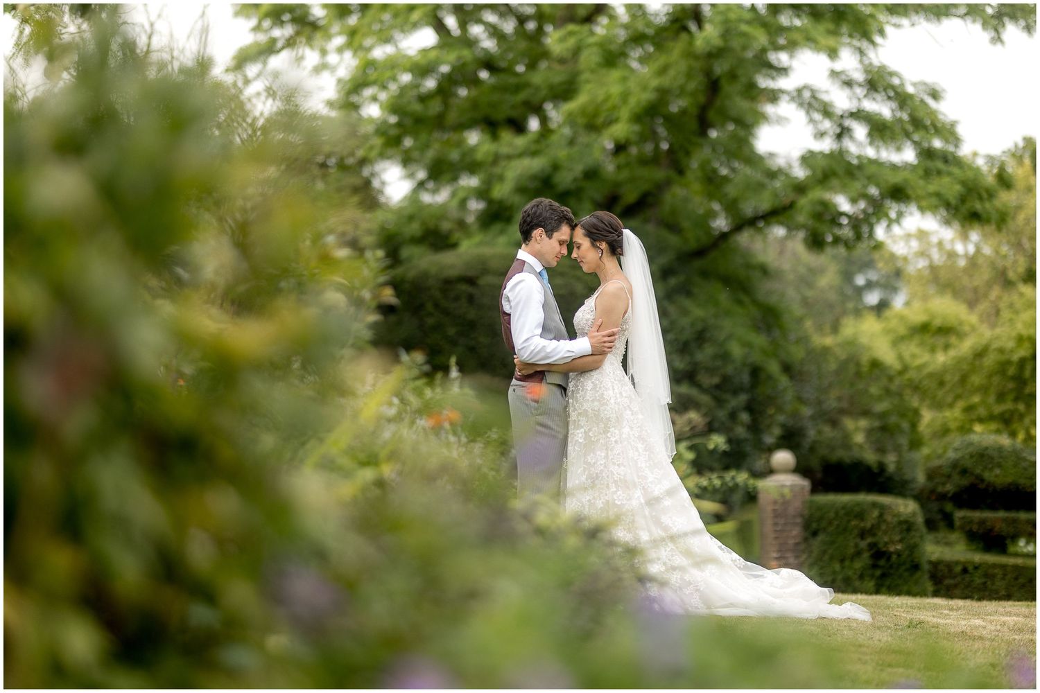 Romantic wedding photos captured in a serene garden setting with manicured hedges and natural greenery.