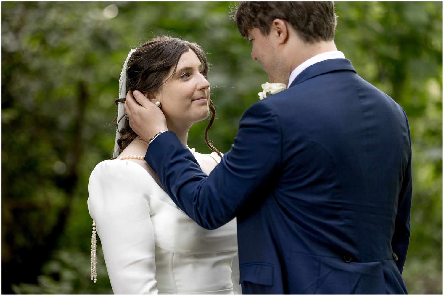 Romantic wedding portrait showing tender moment between bride in white dress and groom in navy suit.