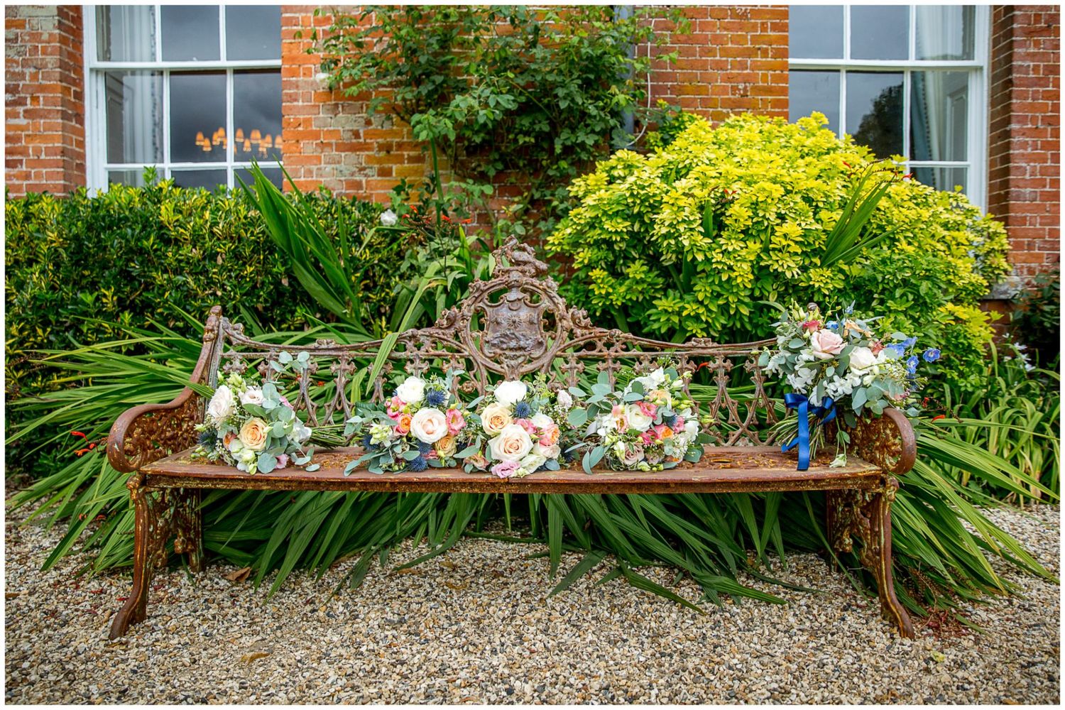 Decorative floral arrangements adorning rustic wooden benches in an English garden setting.
