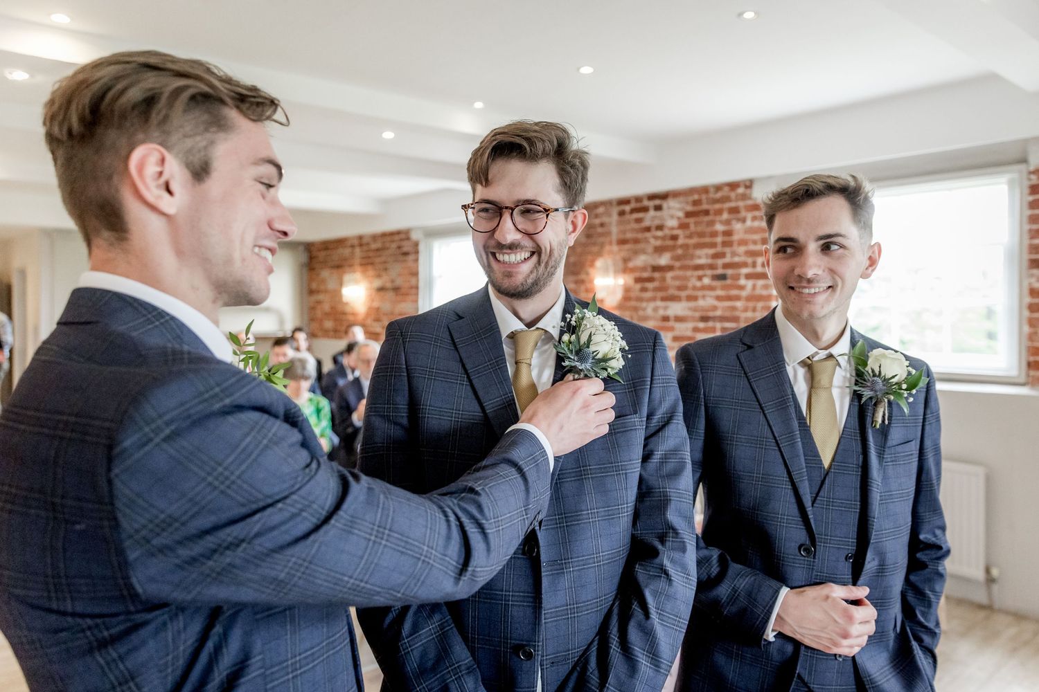 Groomsmen in navy suits share laughs during pre-wedding preparations.