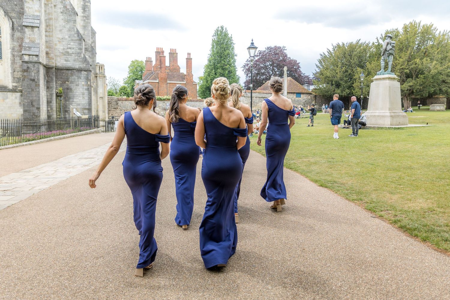 Group in matching navy dresses walking along an outdoor pathway.