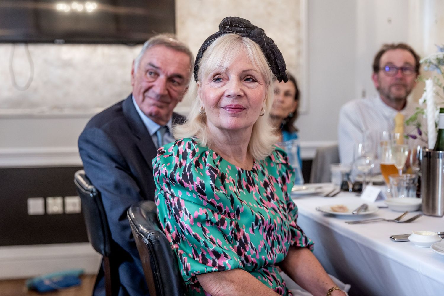 Guests in formal attire share stories and laughter during a wedding reception dinner.