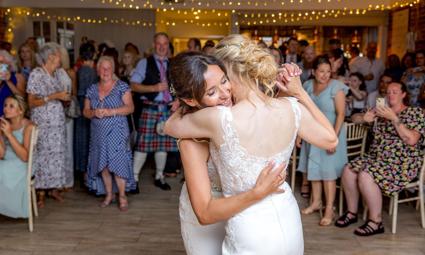 Emotional dance moment under string lights at indoor reception venue.