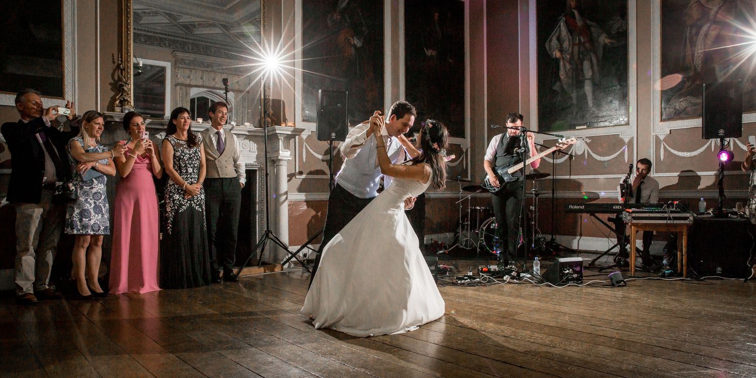 Couples dance together on a dimly lit wooden floor during an evening reception.