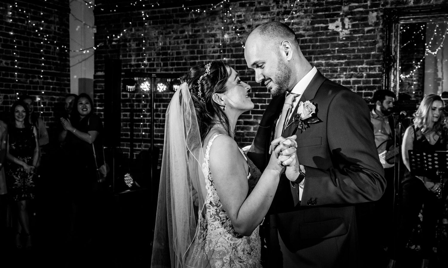 Black and white photo of a celebration in a rustic brick-walled venue.