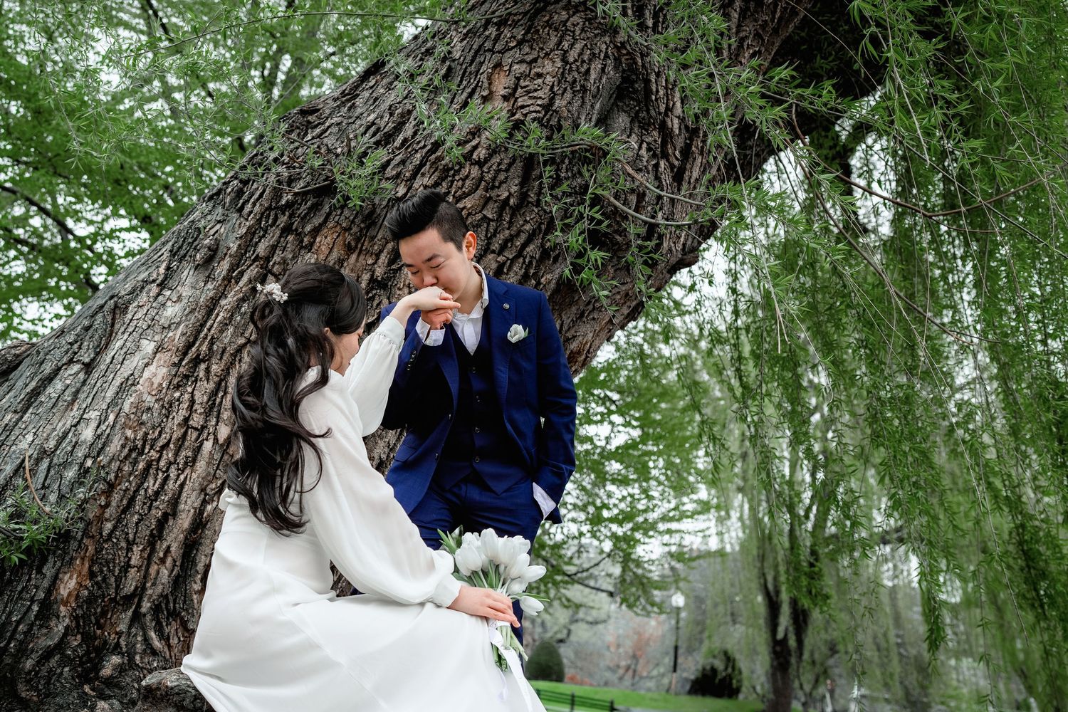 A romantic wedding photo shoot in a lush green forest with trees creating a natural archway.