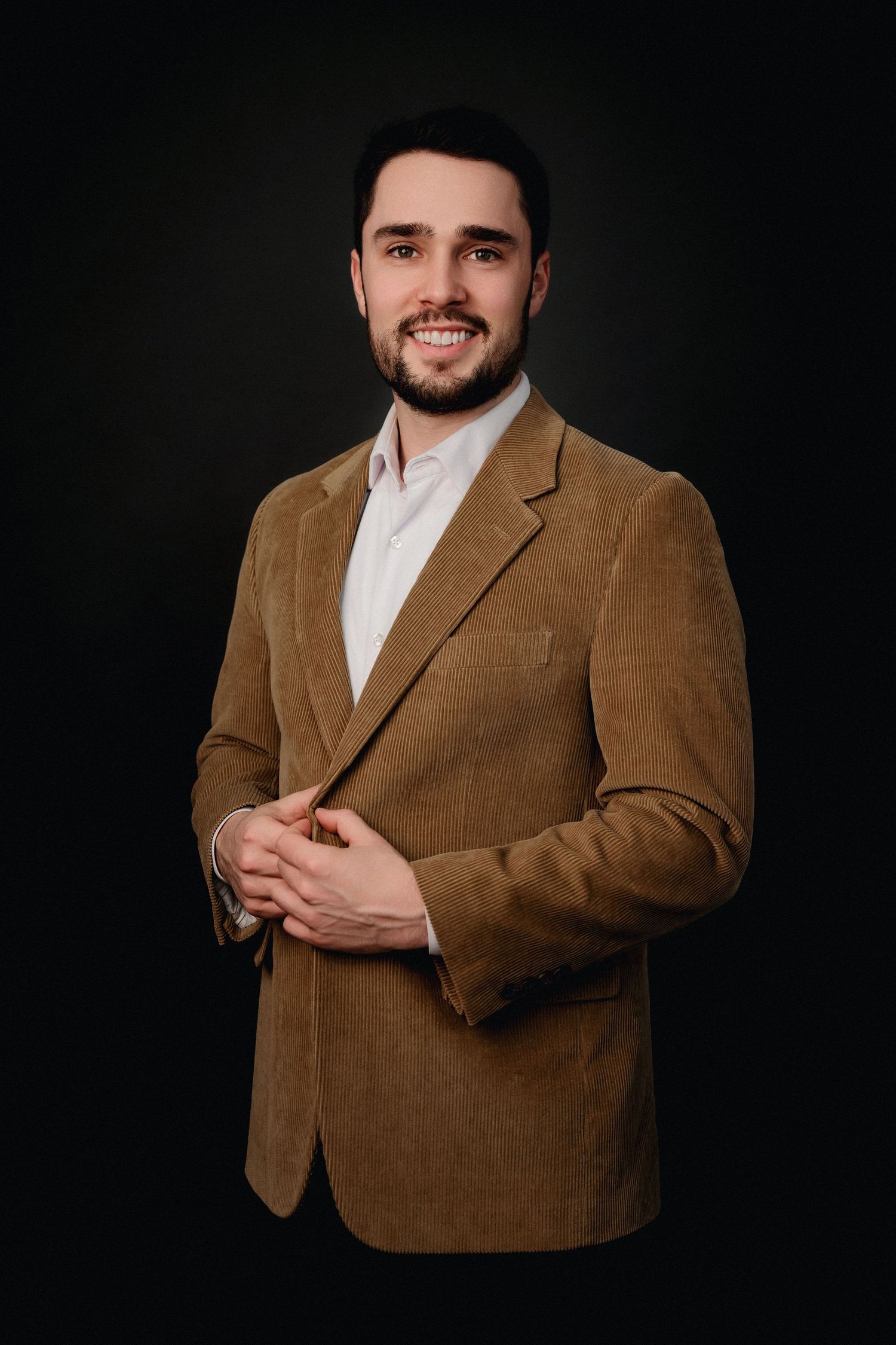 Professional studio portraits of a person wearing a brown corduroy blazer and white shirt against a black background.