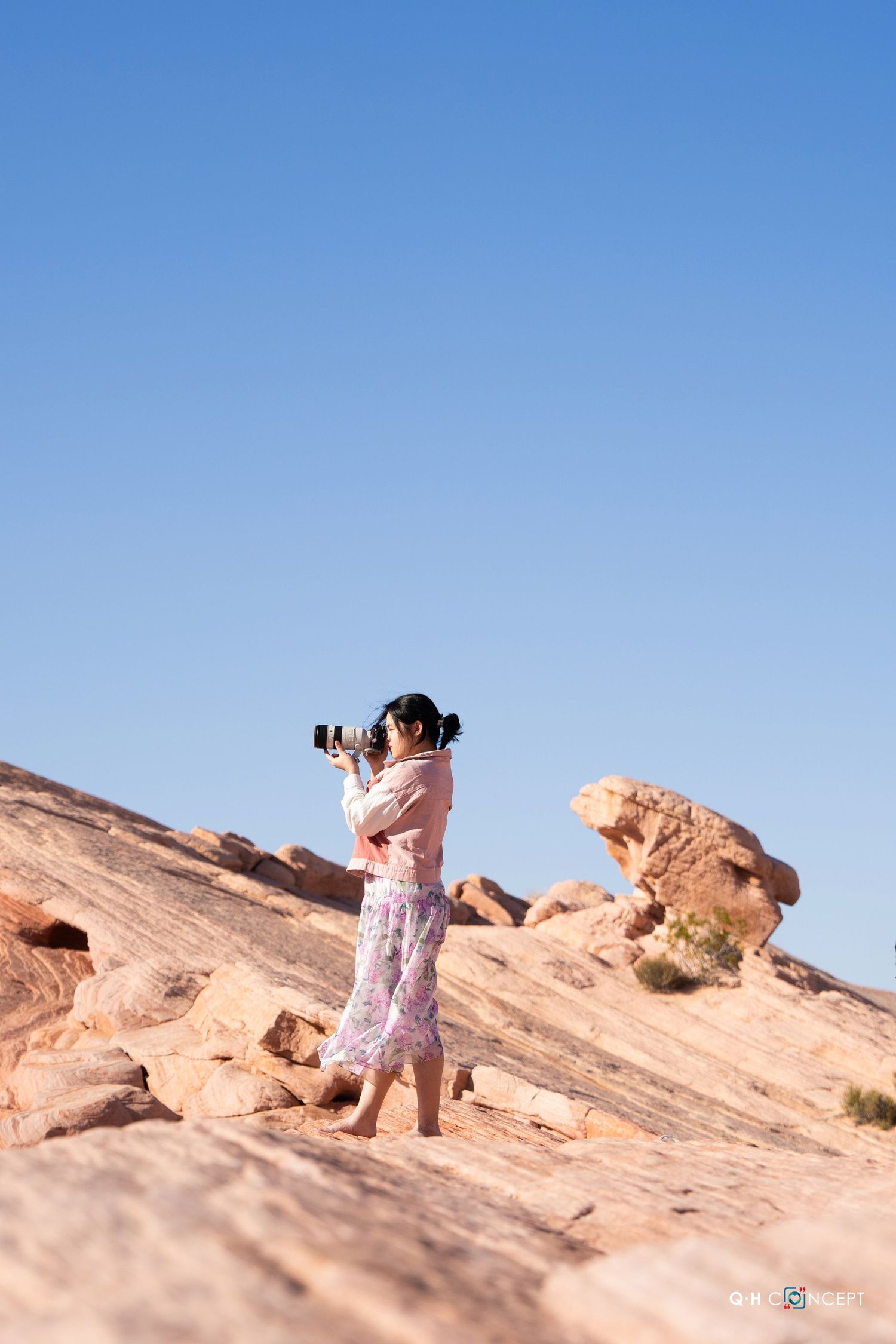Photographer capturing shots on red rock formations in desert landscape.