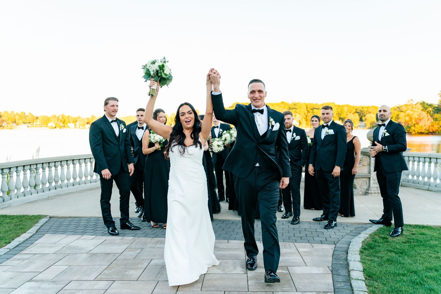 Outdoor wedding ceremony on a terrace with white chairs and guests watching the couple during golden hour.