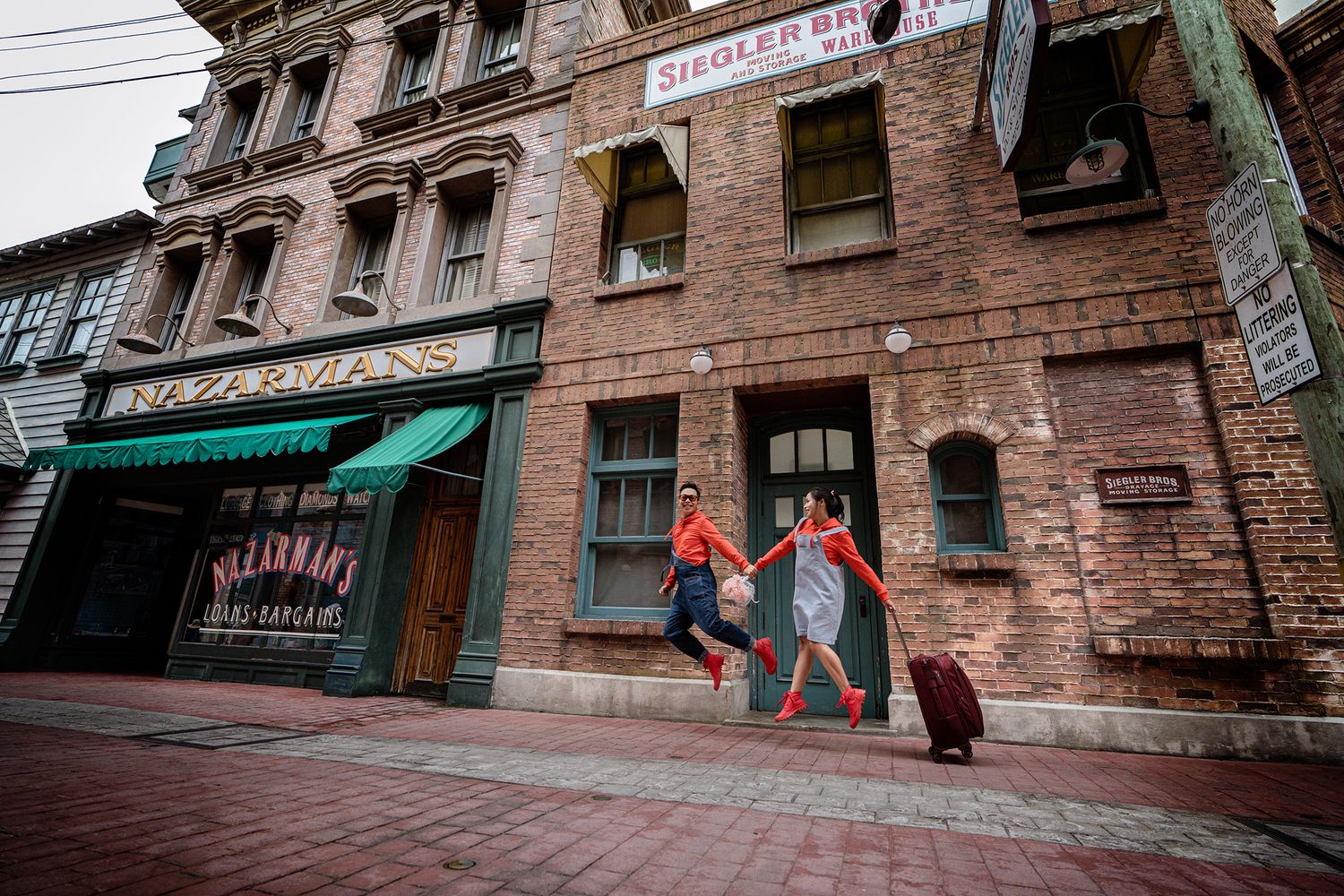 Historic brick buildings with storefronts line a narrow street in Glasgow's Merchant City district.