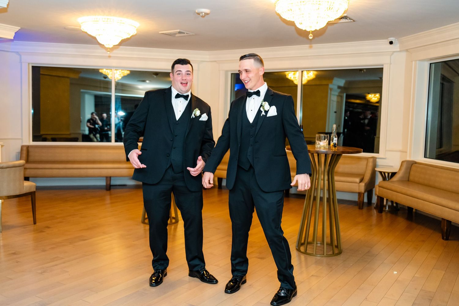 Groomsmen strike playful poses during wedding reception in an elegant ballroom.