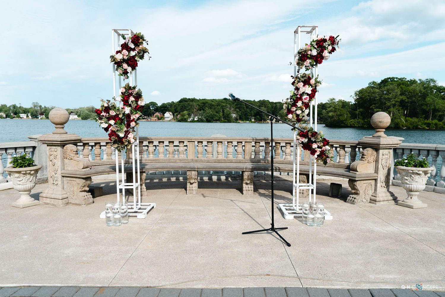 Wide stone terrace with decorative balustrade and flowering branches overlooking a scenic waterfront landscape.