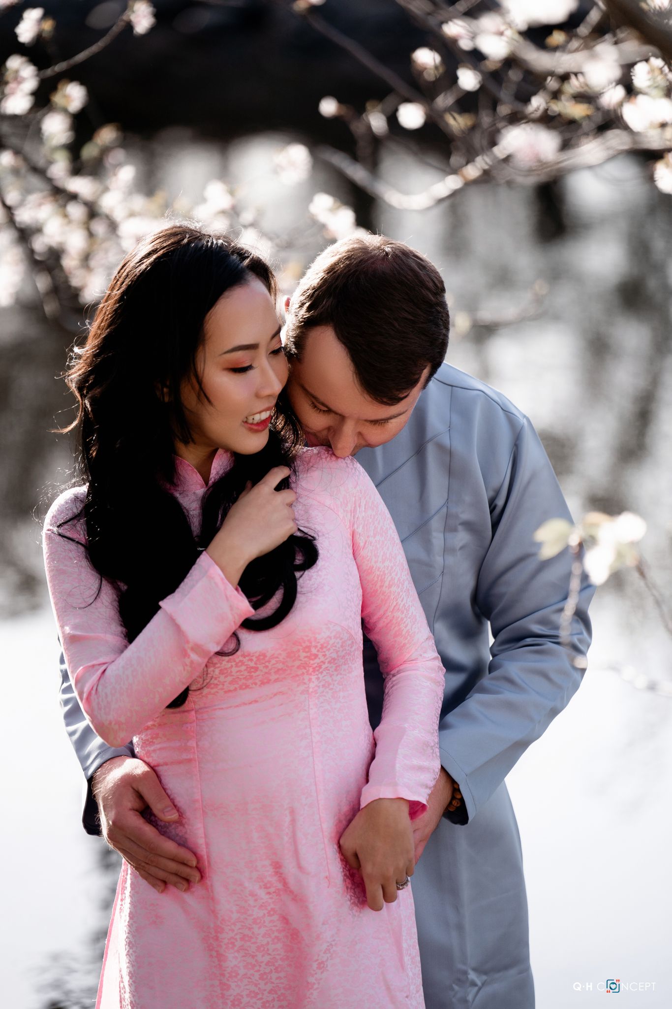 Intimate couple portraits captured among blooming cherry blossoms in soft lighting.