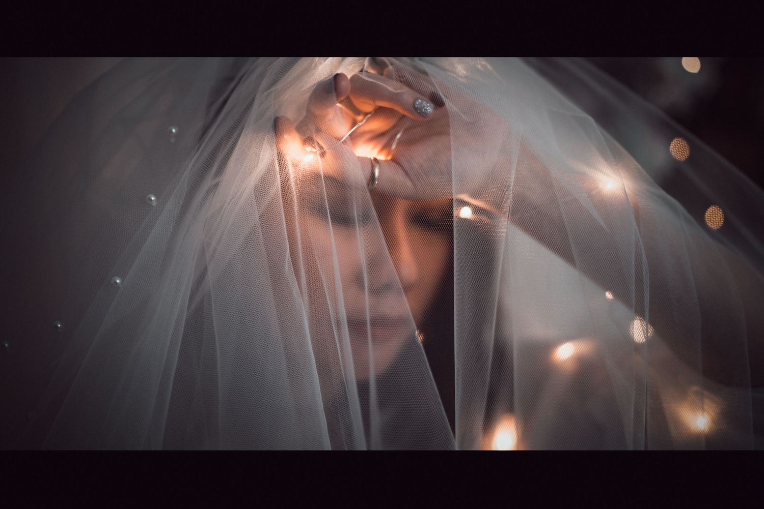 Artistic portrait through a veil with dramatic lighting and bokeh effects.