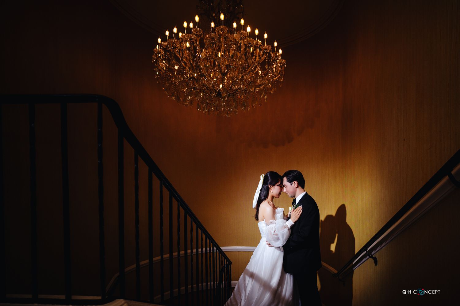 Romantic wedding portraits under a crystal chandelier in warm atmospheric lighting.