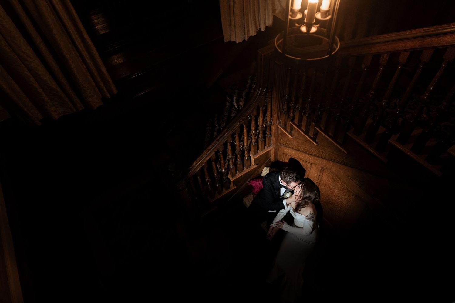 Dramatic silhouette of couple dancing under chandelier in elegant ballroom.