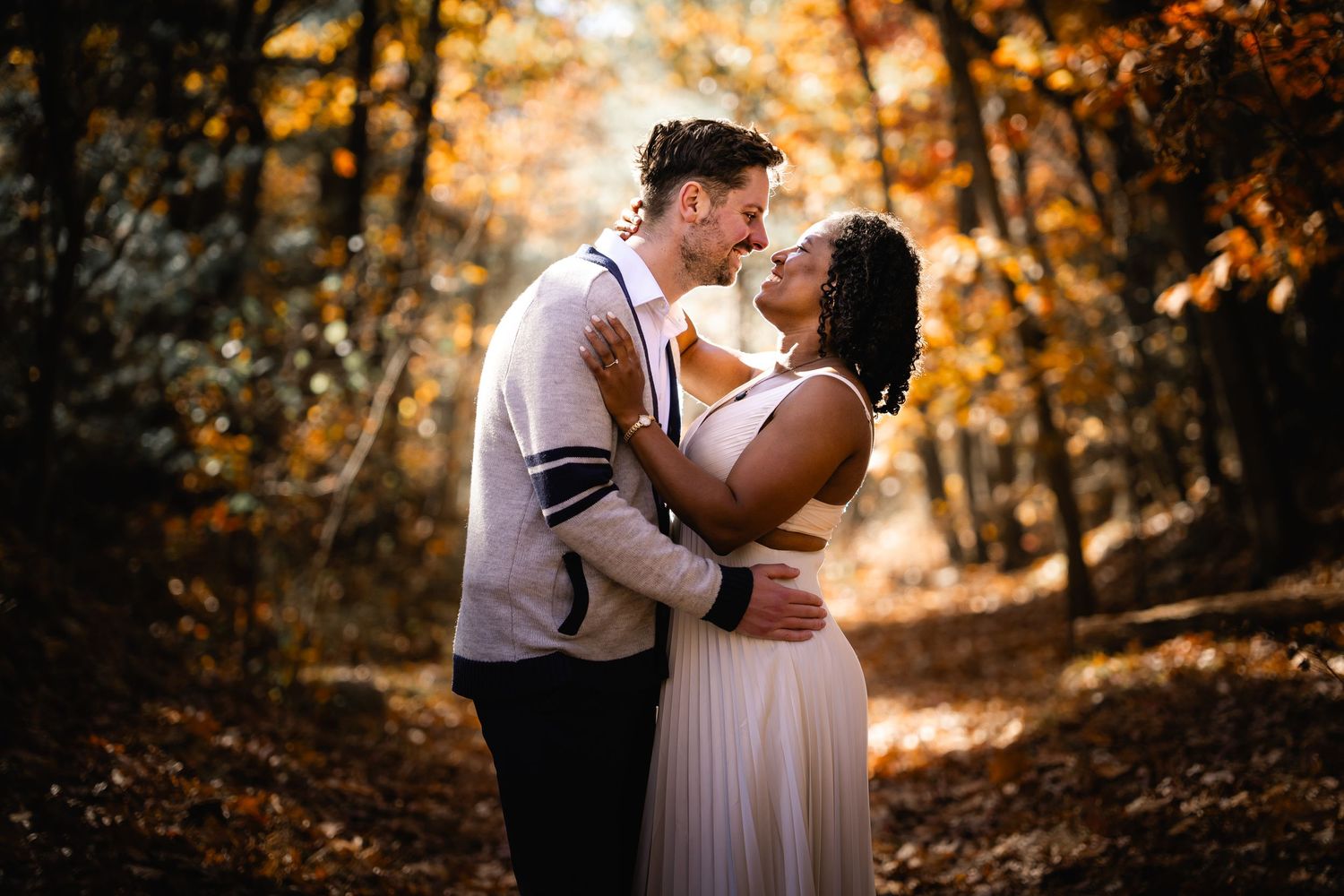 Intimate moment between couple on a fall forest trail with warm autumn colors surrounding them.