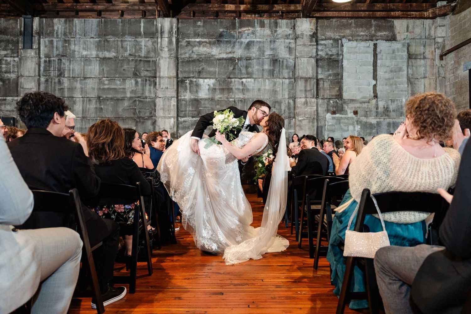 Wedding reception dance in a rustic brick venue with guests celebrating on the dance floor.