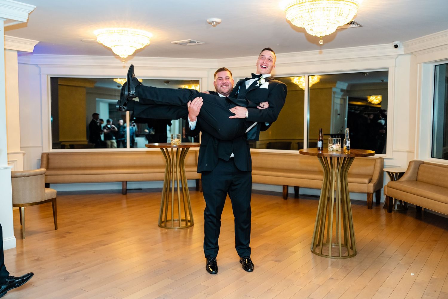 Person in formal attire poses playfully in ballroom with gold cocktail tables.