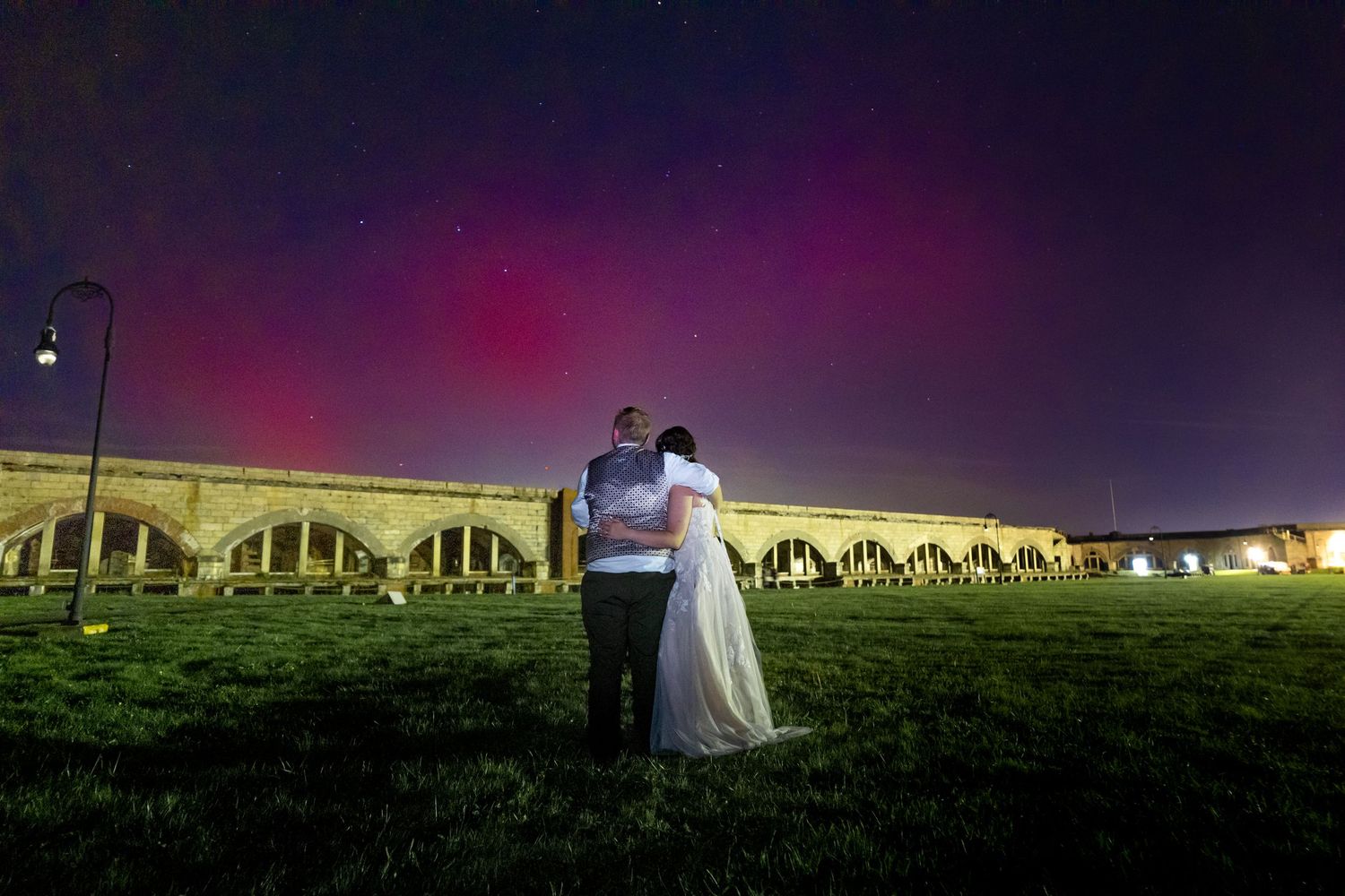 Romantic wedding photos taken under a dramatic purple and green aurora borealis sky at night.