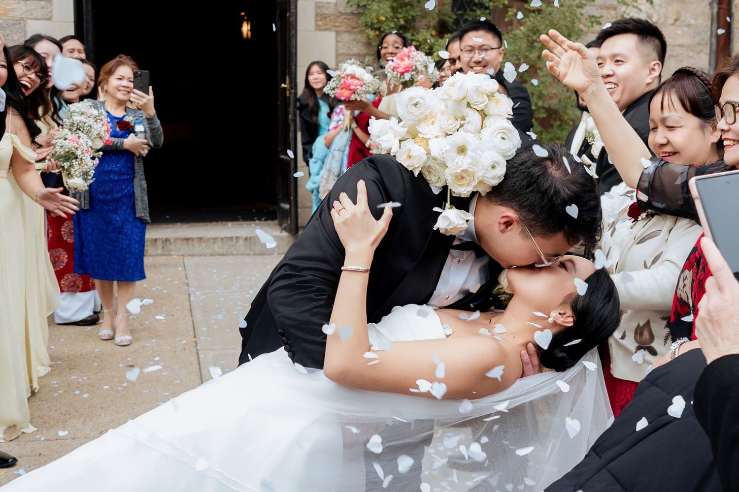 Wedding guests shower newlyweds with confetti during an outdoor celebration.