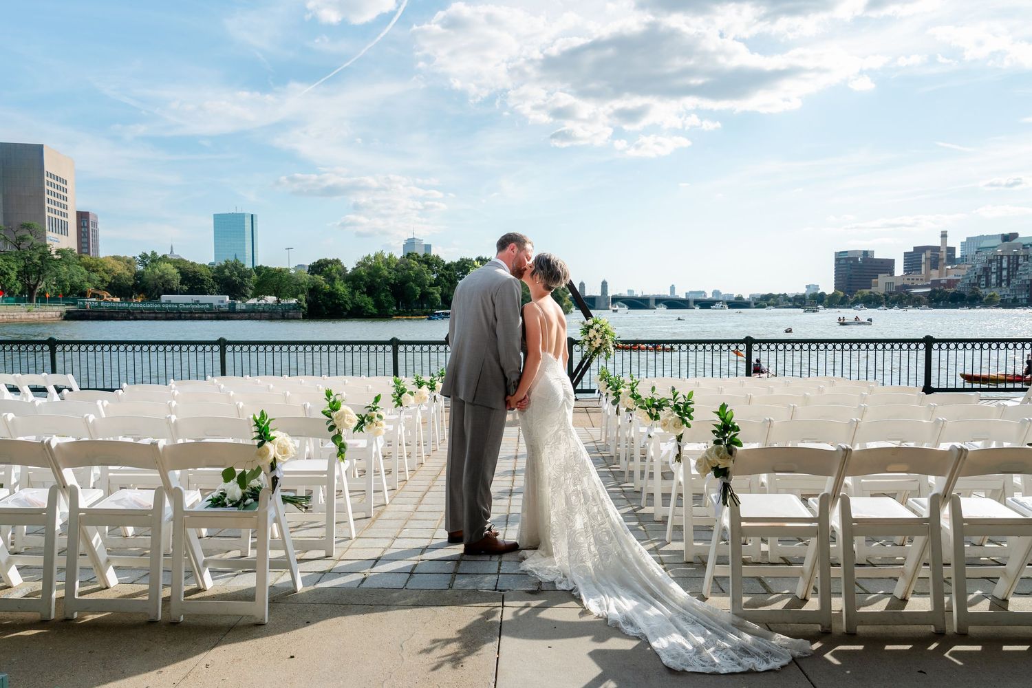 Wedding ceremony setup with white chairs overlooking a scenic waterfront view in Boston on a sunny day.