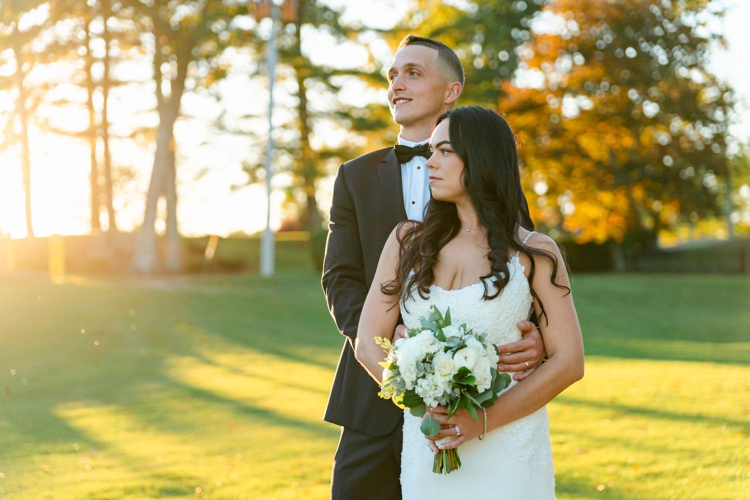 Wedding couple walking together on lush green golf course during golden hour sunset.