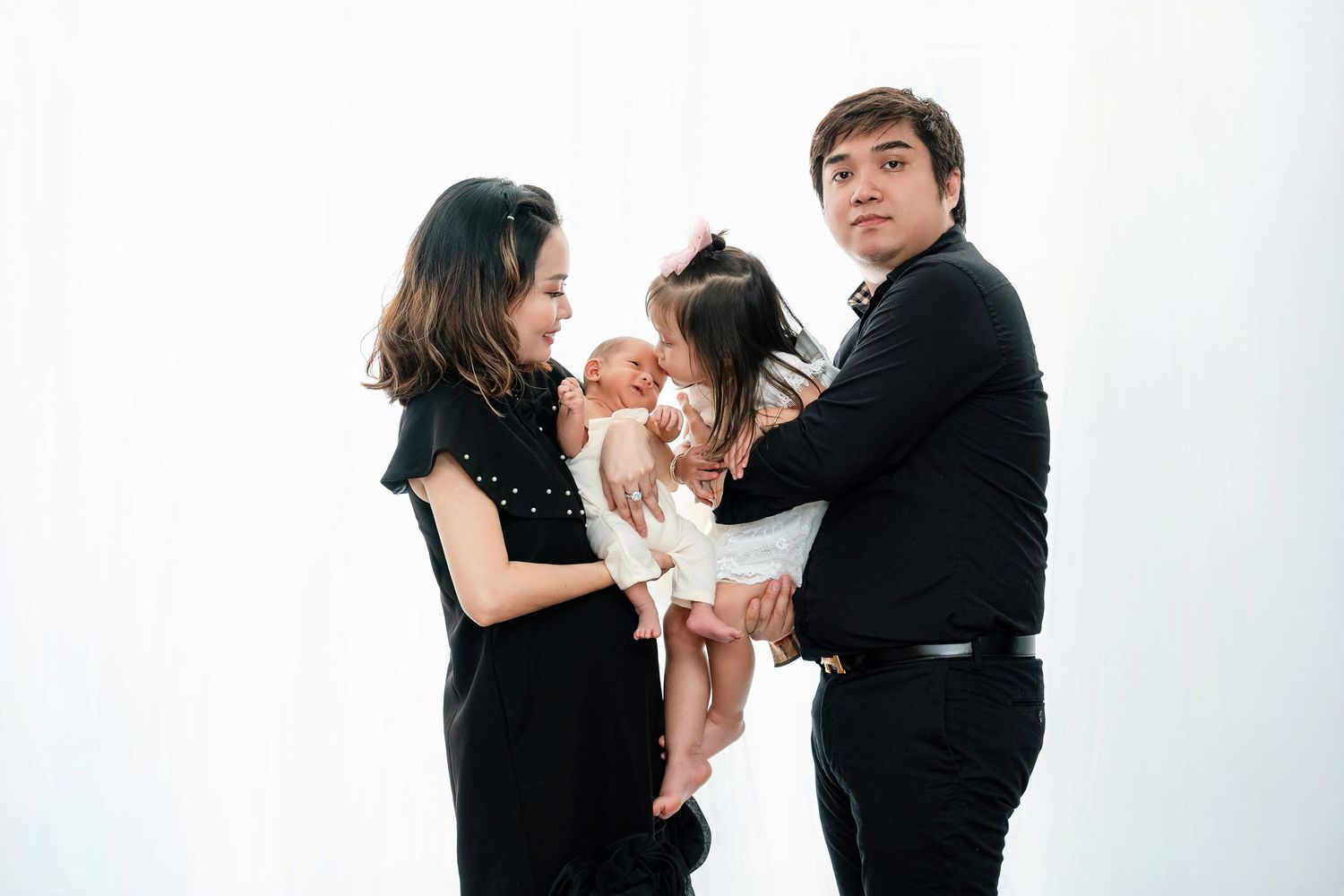 A family in black attire posing together against white background.