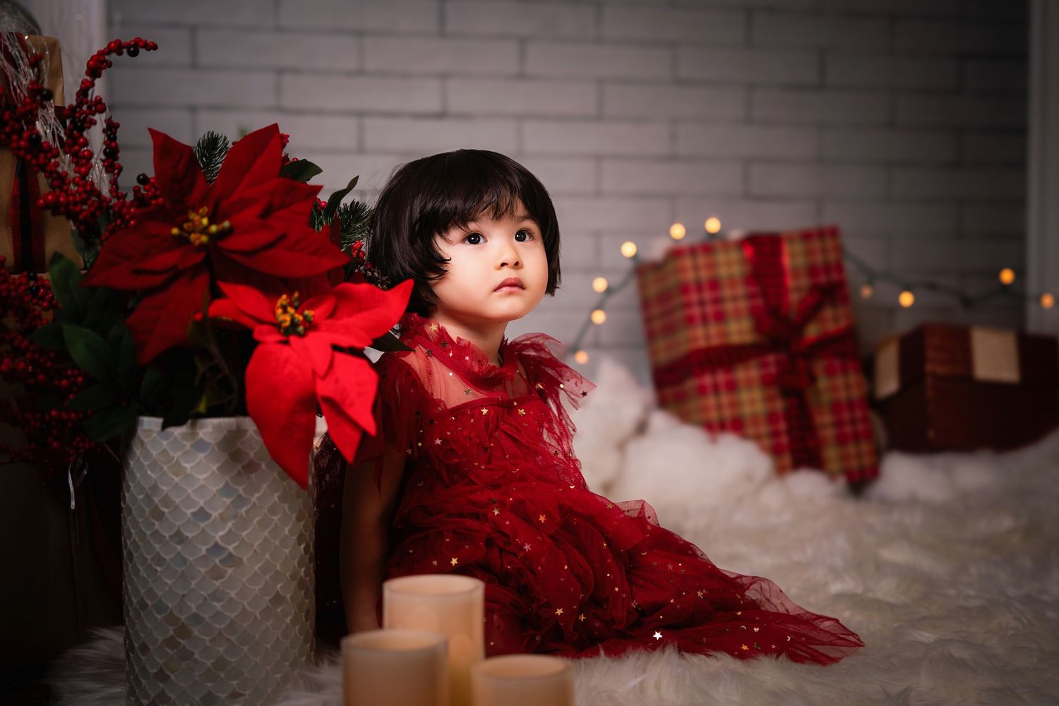 Festive Christmas scene with red poinsettias, plaid ribbons, and bokeh lights creating a cozy holiday atmosphere.
