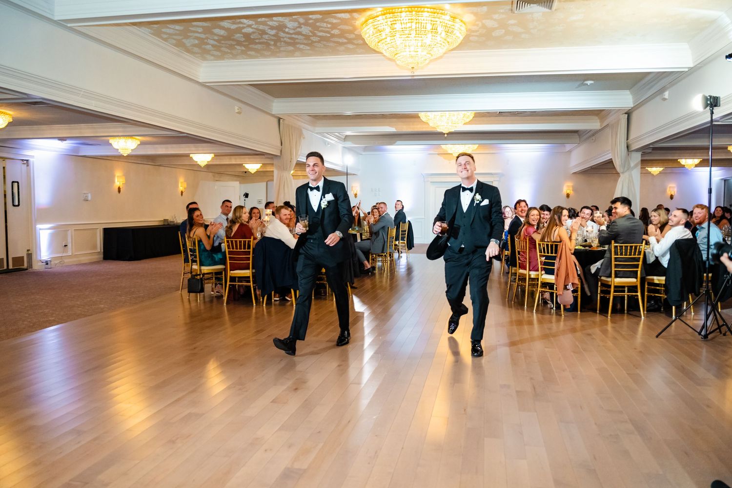 Wide view of a spacious ballroom with guests and dance floor during a wedding reception.